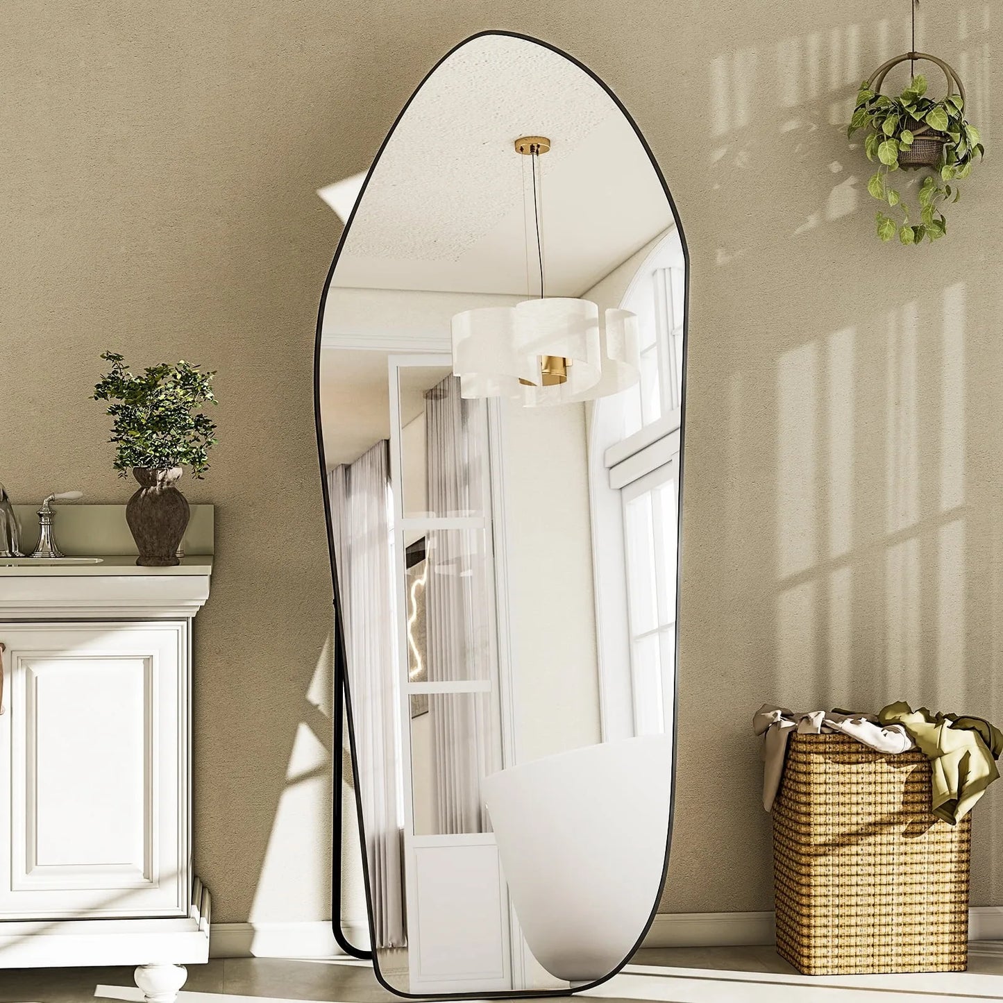 Large oval mirror in a room with a white cabinet, plant, and basket.